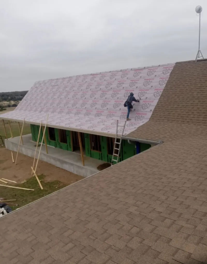 Worker preparing underlayment for a metal roof installation in North Whitehall